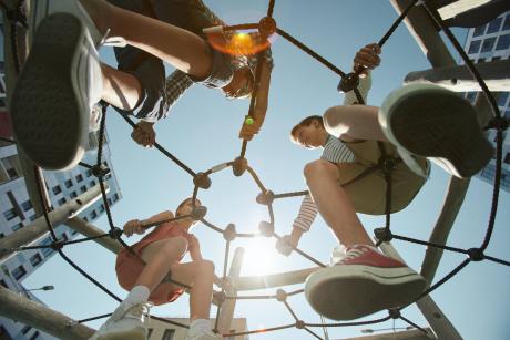 Drie kinderen lachen naar elkaar op een speeltuin